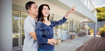 Composite image of happy couple with woman pointing up