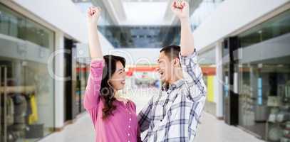 Composite image of cheerful young couple with hands raised