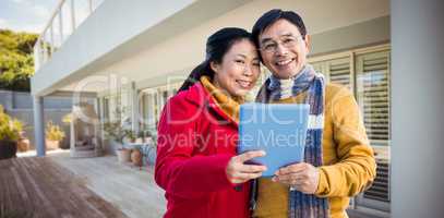 Composite image of asian couple on balcony using tablet