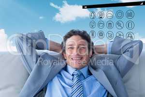 Composite image of businessman smiling at camera sitting on couc