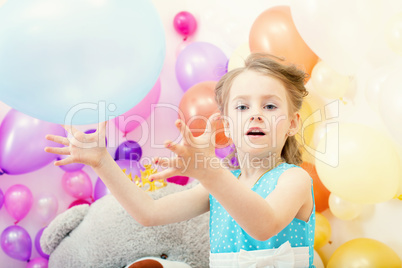 Funny little girl plays with balloon in studio