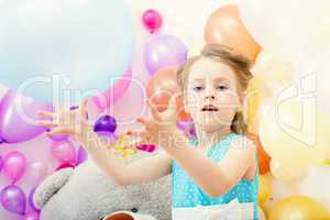 Funny little girl plays with balloon in studio