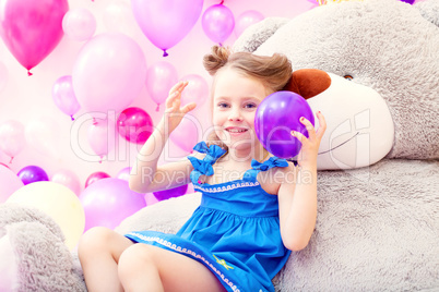 Cheerful girl plays with balloon in playroom