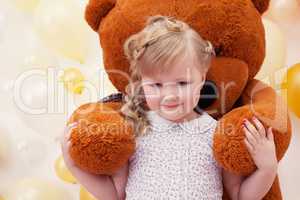 Cute little girl in arms of large teddy bear