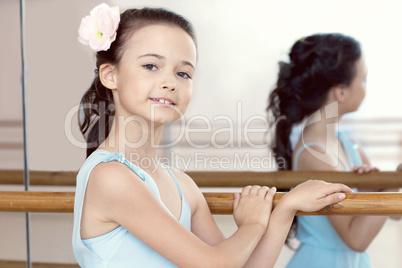Portrait of adorable ballerina posing with barre