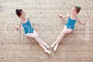 Two little ballerinas posing on wooden floor