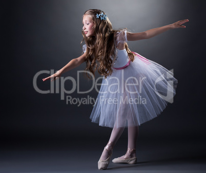Charming curly girl dancing ballet in studio