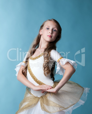 Proud young ballerina posing on blue backdrop