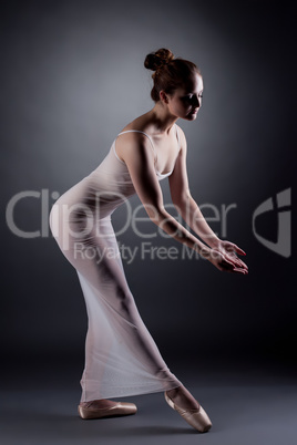 Sexy ballerina dancing in studio, on gray backdrop