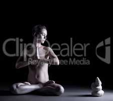 Nude girl with shimmering skin meditates in studio