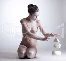 Pretty naked woman raises stones power of thought