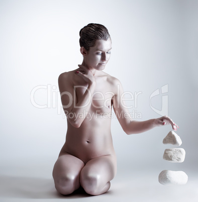 Relaxed nude woman raises stones mentally