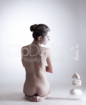 Image of naked female yogi mentally moving stones