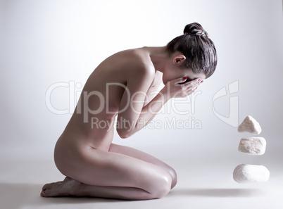 Nude female yogi mentally controls stones