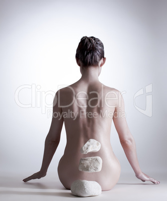 Rear view of naked woman mentally moving stones