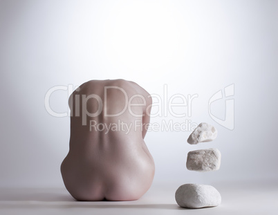 Rear view of nude girl mentally commands stones