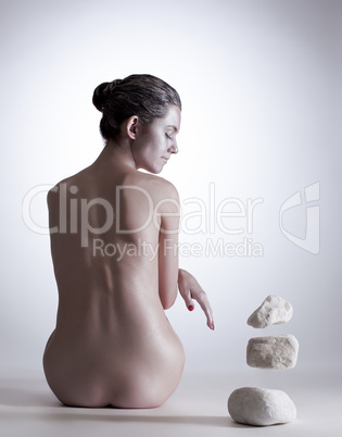 Rear view of nude woman controls stones