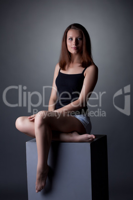 Lovely slim woman posing sitting on cube