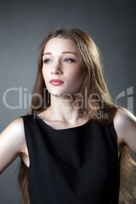 Portrait of cute long-haired girl on gray backdrop