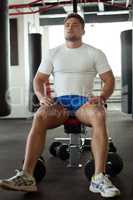 Muscular athlete posing sitting on simulator