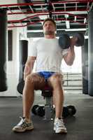 Handsome man exercising with dumbbells in gym