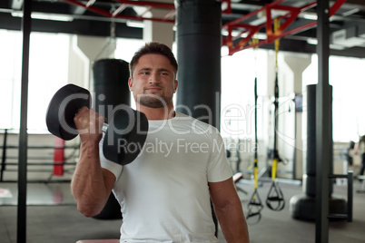 Portrait of strong man exercising with dumbbells