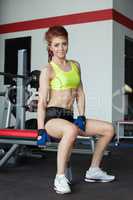 Attractive red-haired female athlete posing in gym