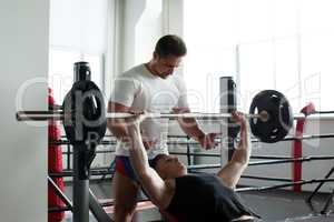 Coach insures athlete exercising with barbell