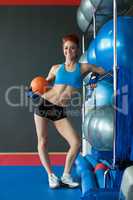 Happy muscular woman posing with basketball ball