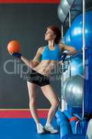 Cute sportswoman posing with balls in gym