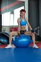 Funny female athlete sitting on gymnastic ball