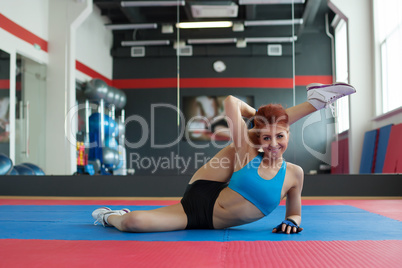 Smiling sportswoman doing stretching exercises