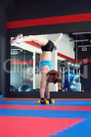 Redhead muscled female athlete does handstand