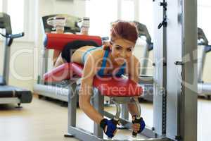 Cheerful girl posing exercising on bench in gym