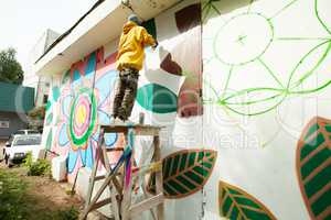 Image of man paints on wall with spray can