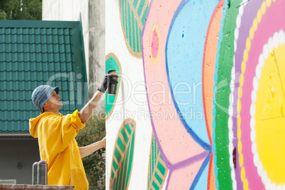Creative young man drawing with spray can on wall