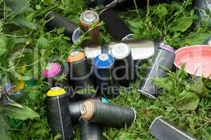 Colorful cans of paint on grass