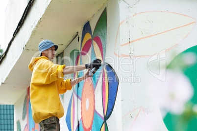 Image of man paints on wall with spray can