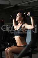 Sexy young brunette exercising with dumbbells