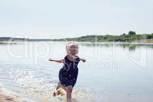 Cheerful little girl runs along river