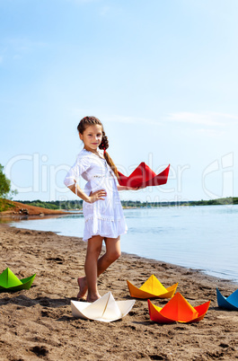 Cute little girl posing with colorful paper boats