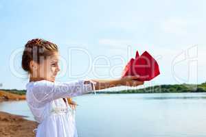 Adorable little girl holding red paper boat