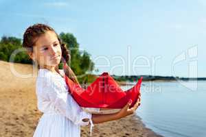 Sweet little girl cuddles paper boat