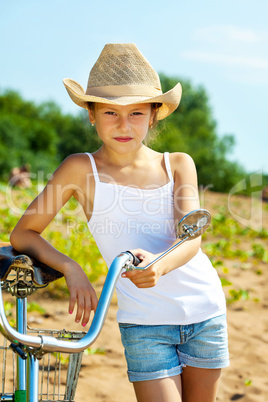 Stylish young girl in casual wear posing with bike