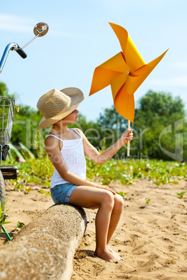 Adorable girl playing with paper windmill