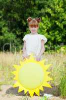 Pretty red-haired girl posing with paper sun