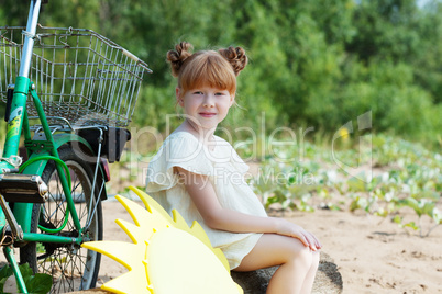 Funny red-haired little girl posing with bicycle