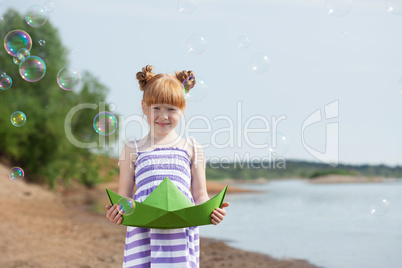 Playful girl posing with paper boat and bubbles