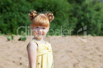 Adorable red-haired girl posing at camera in park