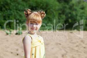 Adorable red-haired girl posing at camera in park